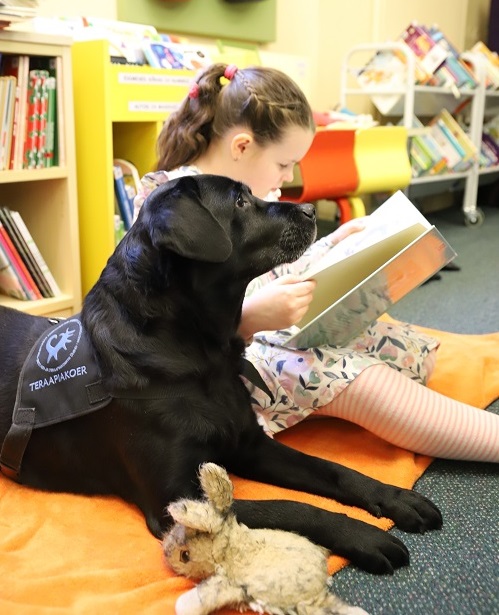 Tüdruk loeb koos koeraga raamatut
